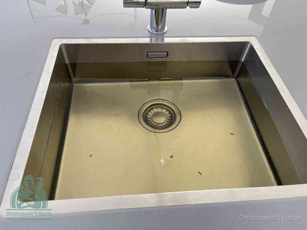 Stilstaand water in een rvs spoelbak dat niet wegloopt, een duidelijk signaal van een gootsteenverstopping in t Harde