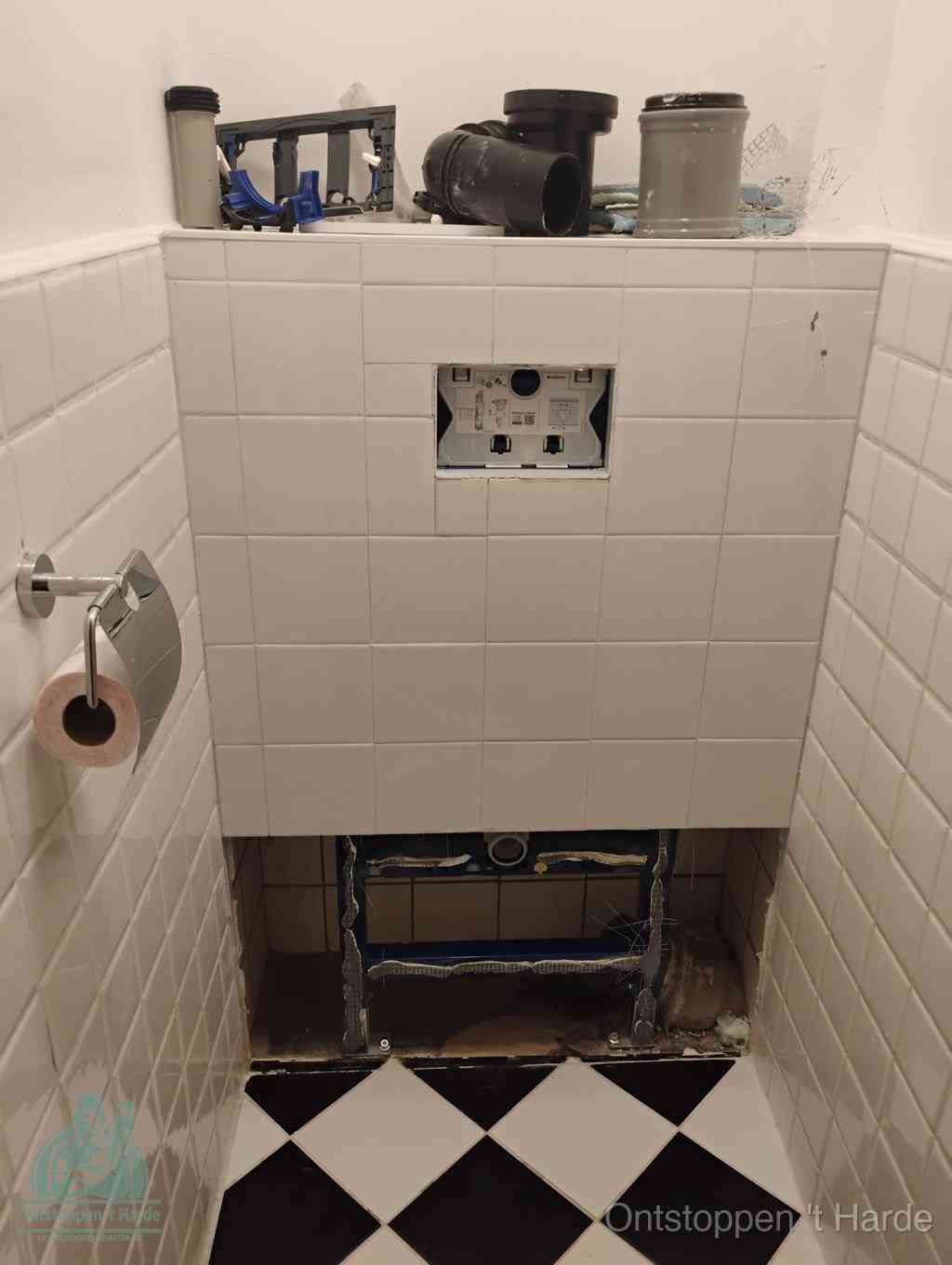 Een toiletruimte waar het hangtoilet en de inbouwreservoir-onderdelen zijn vrijgelegd voor onderhoud, periodiek nazicht voorkomt een wc-verstopping in t Harde